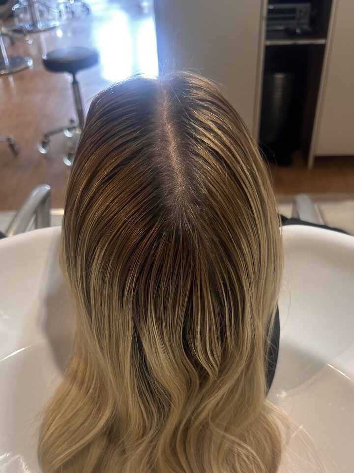 Hair with regrowth and faded lengths at the basin, before the correction
